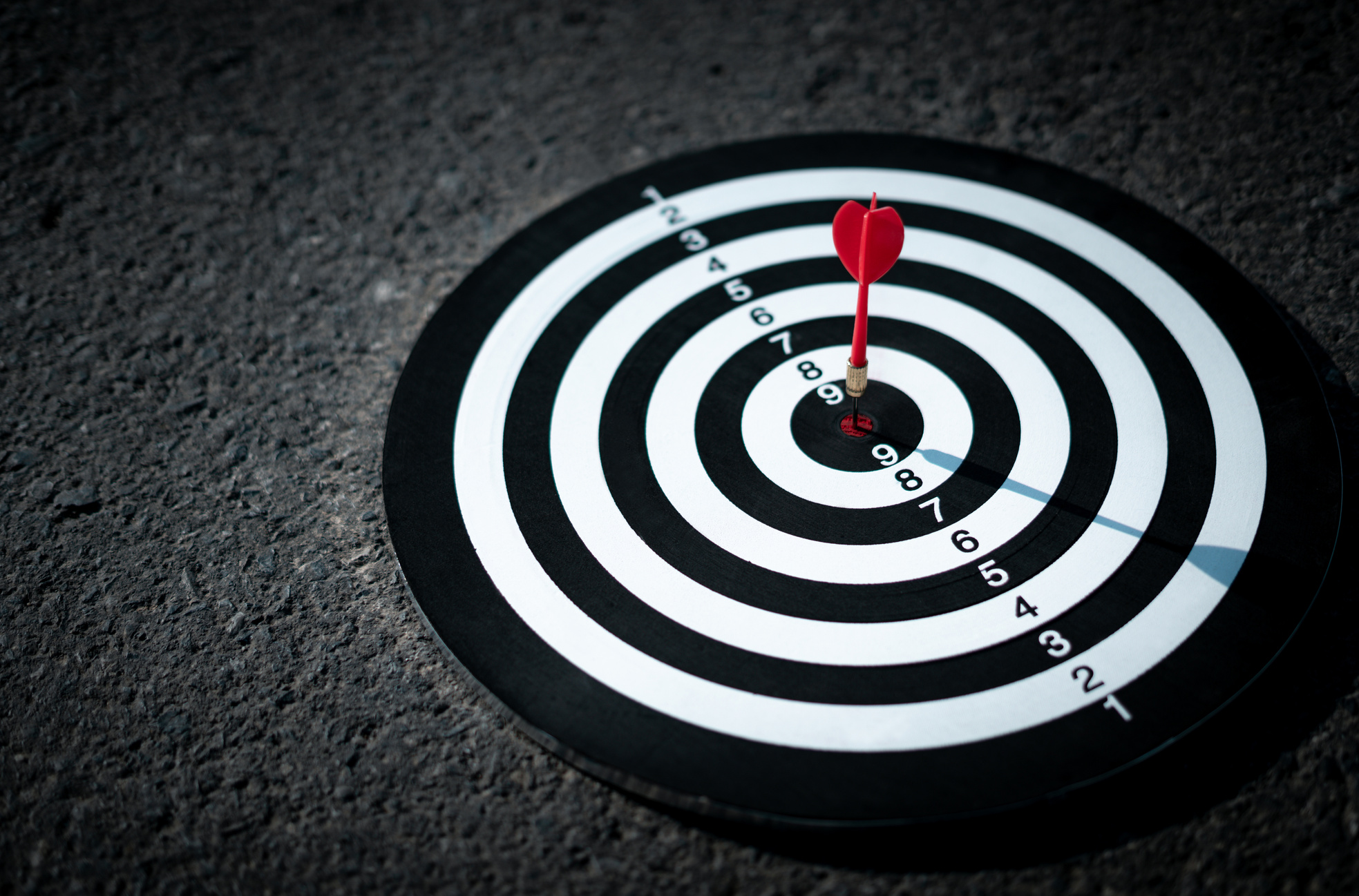 The red arrow hits the target in the center of the dartboard on the road. , The concept of setting goals for marketing, investment, and success in work. Achieve objectives, focus on specific points.